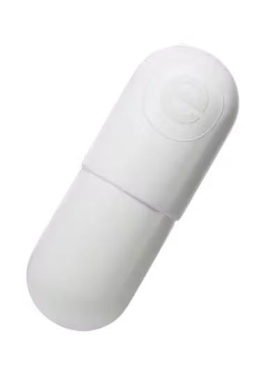 Uma cápsula branca está posicionada diagonalmente contra um fundo preto. Uma parte da cápsula é levemente menor e se encaixa sobre a outra parte, sugerindo um design de duas peças.